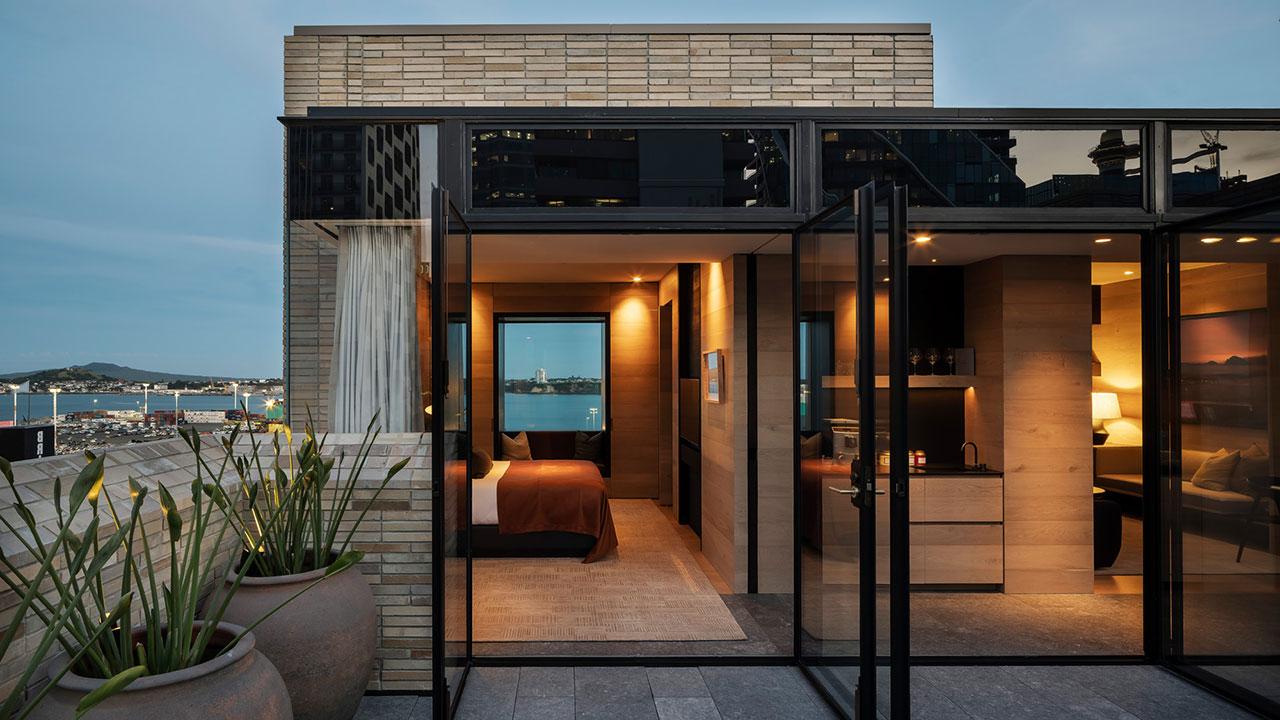 A hotel room at Hotel Britomart with floor-to-ceiling glass doors open to a rooftop outdoor space